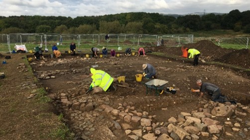 A photograph showing archaeologists excavating the manor house.